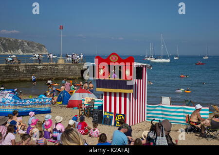 Les vacanciers appréciant Punch et Judy sur la plage de Swanage dorset Banque D'Images