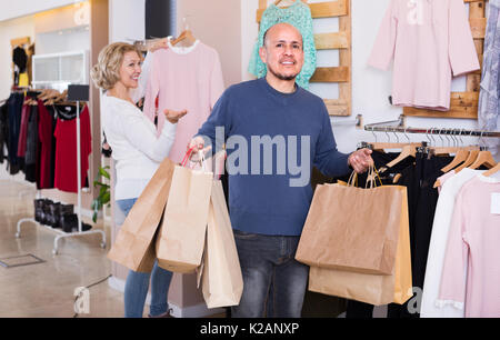 Mari mature fatigué en attente de woman shopping in clothing store Banque D'Images