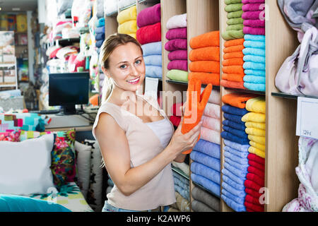 Jeune femme gaie d'acheter des serviettes douces en accueil boutique textile Banque D'Images