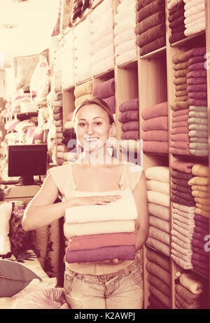 Jeune femme joyeuse préparation à la clientèle dans les serviettes de bain multicolore département textile Banque D'Images