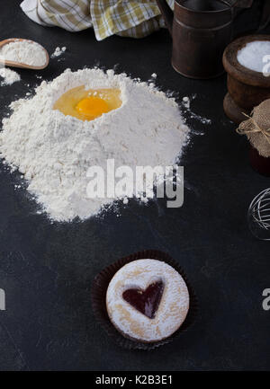 Pastry biscuit, une contre-coeur rouge et le sucre en poudre et d'ustensiles de cuisine sur la table Banque D'Images