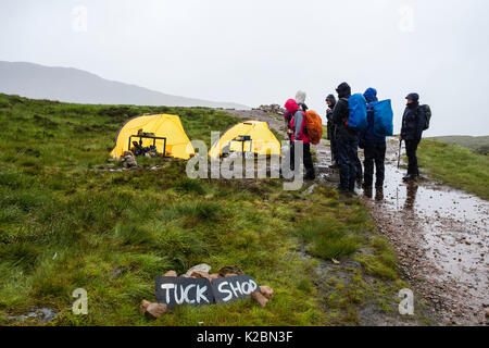 Randonnée Les randonneurs par Tuck Shop tentes sur West Highland Way chemin sentier point le plus élevé en haut de l'Escalier Diables dans la pluie. Glen Coe, Highland, Scotland, UK Banque D'Images