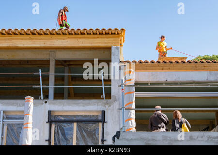 Les couvreurs travaillent sur carrelage le toit d'une nouvelle maison en construction sur la côte d'Azur dans le sud de la France Banque D'Images