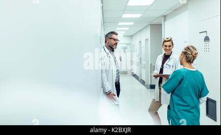 L'équipe médicale de discuter dans le couloir à l'hôpital. Discuter avec des collègues médecin mature tout en se tenant dans le couloir de l'hôpital. Banque D'Images