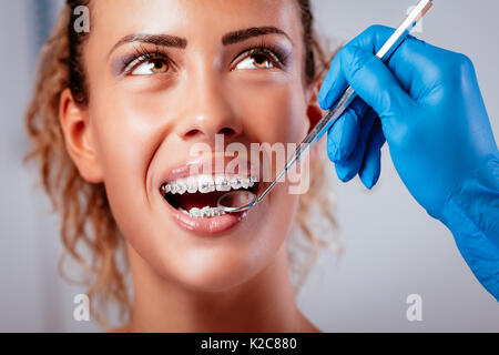 Close-up d'un dentiste contrôle accolades avec un miroir dentaire sur la  jeune patiente Photo Stock - Alamy
