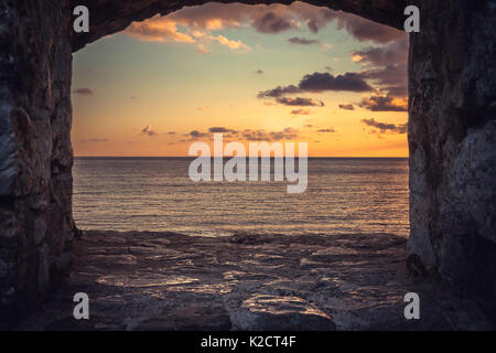 Voir de magnifique coucher de soleil sur mer à l'aide de fenêtre vieux bâtiment avec ciel dramatique et vue en perspective Banque D'Images