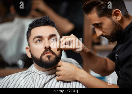 Bel homme visitant barbershop pour corection du pain. Banque D'Images