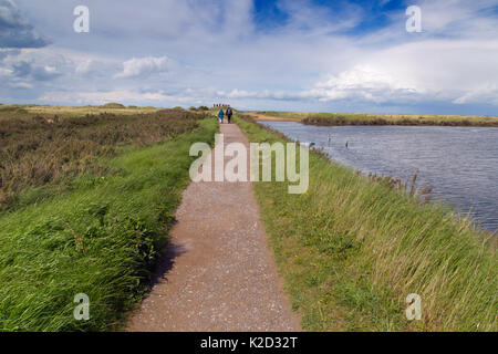 Les gens qui marchent le long du sentier côtier à à Titchwell RSPB Réserve Naturelle, Norfolk, UK, mai 2015. Banque D'Images