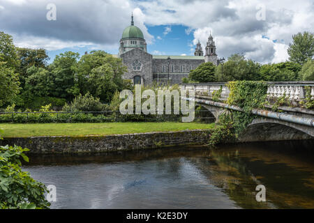 Galway, Irlande - Août 5, 2017 : la cathédrale bâtiment avec dome et Salmon Weir Bridge qui mène à elle. En vertu de cloudscape vu que depuis Corrib Rive Banque D'Images