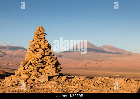 Apacheta / Apachita - un cairn de pierre dans les Andes, un petit tas de pierres construites le long de la piste en haute montagne avec le volcan Licancabur (5916 m au-dessus du niveau de la mer) et Juriques volcan jusqu'à l'extrême droite (5704 m) en arrière-plan, Désert d'Atacama, San Pedro, Chili Banque D'Images