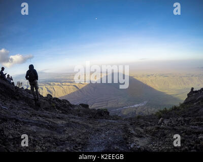 Les gens qui regardent l'ombre de l'Ol Doinyo (Lengei La Montagne de Dieu) s'étendent au-dessous du lac Natron au crépuscule et de la vallée du Rift, en Tanzanie 2015 Banque D'Images