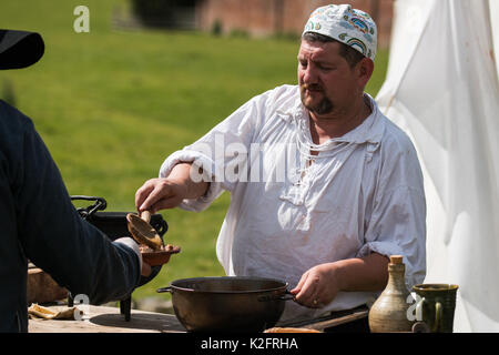 Une guerre civile anglaise reenactor cook sert de ragoût un pot de fer noir. HELMSLEY, NORTH YORKSHIRE, UK - Aug 12, 2017 Banque D'Images