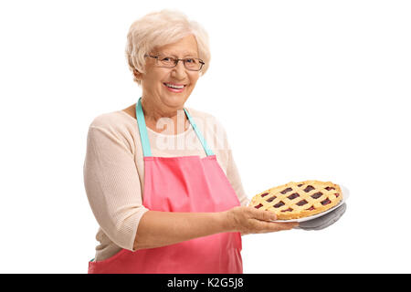 Vieille Femme tenant un gâteau fraîchement cuit au four isolé sur fond blanc Banque D'Images