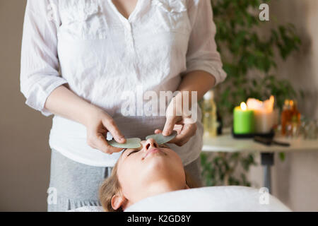 Jeune jolie femme massage du visage ou un soin de beauté au spa salon Banque D'Images