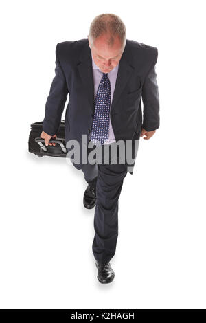 Photo prise à la verticale d'un businessman en costume tirant une valise, isolé sur un fond blanc. Banque D'Images