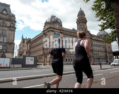 Un homme et une femme en jogging avant de Co-operative House dans la rue dans la région de Kingston sur le côté sud de la rivière Clyde à Glasgow Banque D'Images