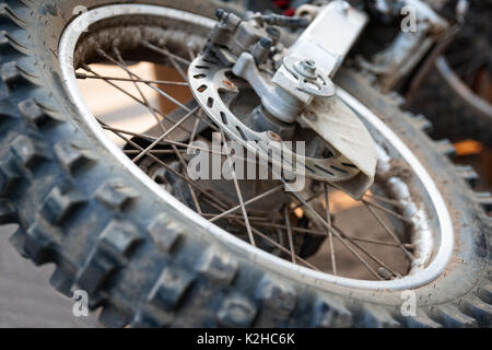 Vue rapprochée d'une roue arrière et moyeu de roue d'entraînement d'une sale, grunge, moto motocross qui jette sur le sol. Banque D'Images