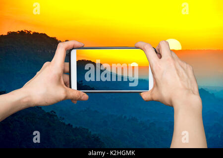 Girl taking photos sur téléphone intelligent au lever du soleil sur la montagne du Parc National de Pha Taem,Thailand Banque D'Images