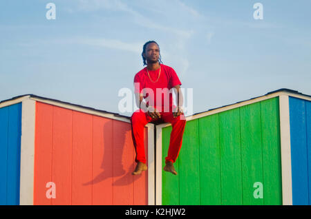 Homme assis sur le haut de plage multicolores house Banque D'Images