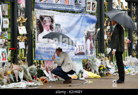 Le duc de Cambridge fleurs feuilles comme lui et le prince Harry regarde des hommages à Diana, princesse de Galles attaché à la porte d'or de Kensington Palace, Londres, avant le 20e anniversaire de la mort de leur mère. Banque D'Images