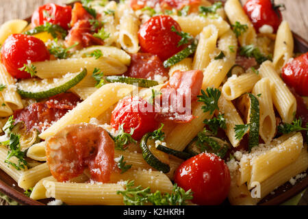 Pâtes penne au jambon, tomates, courgettes et parmesan macro sur une plaque horizontale. Banque D'Images