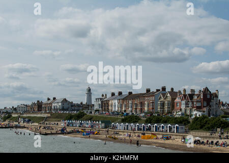 Maison de plage et lumière Southwold Angleterre Southwold plage huts hutte sable personnes dans la mer maisons lumière maison de vacances sable touristes nuages noir bas Banque D'Images