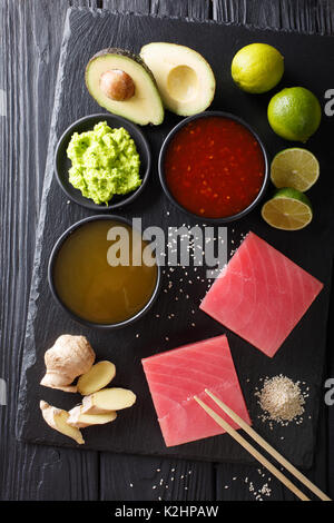 Cuisine japonaise : steak de thon cru avec des ingrédients pour la cuisine gros plan sur la table. Haut de la vue de dessus à la verticale Banque D'Images