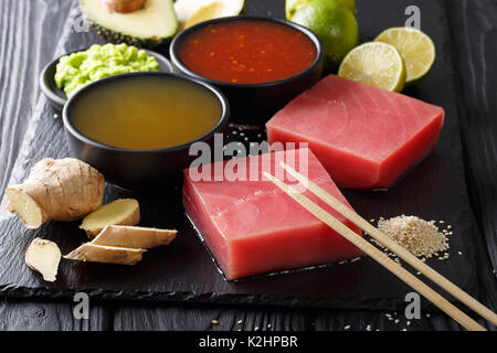 Filet de thon frais crus avec du chili et de l'ananas sauces et d'autres ingrédients pour la cuisine gros plan sur l'arrière-plan horizontal de la table. Banque D'Images