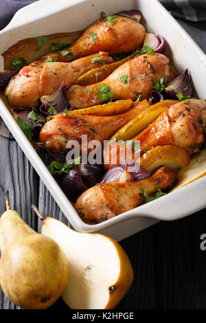 Belle l'alimentation : des cuisses de poulet cuite au four avec oignons rouges, les poires et les verts close-up dans un plat allant au four. vertical Banque D'Images