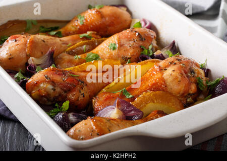 Des pilons de poulet aux poires et oignons rouges en sauce soja-miel close-up dans un plat allant au four. Banque D'Images