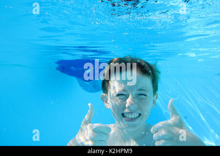Adolescent aux cheveux auburn, putting Thumbs up alors que sous l'eau dans une piscine, à la caméra en Banque D'Images