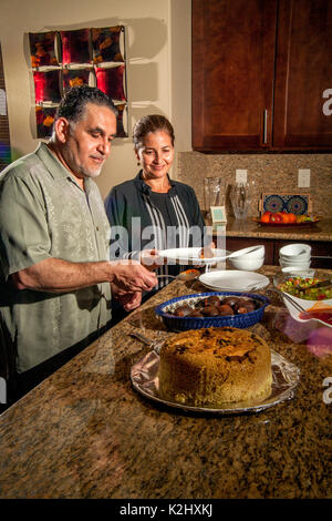 Un couple musulman à Irvine, CA, préparer un dîner avec jordanien ethniques et aubergines farcies de riz assaisonné. Remarque femme en robe traditionnelle. Communiqué de modèle Banque D'Images