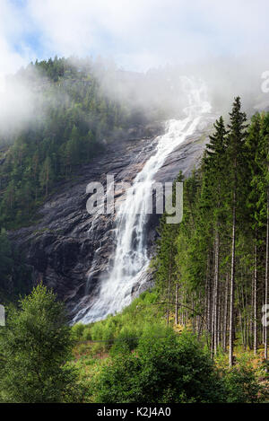 En cascade de l'eau et de mousse en Woodland Waterfall. Glisser les nuages par dans la section haute de l'automne et la forêt environnante. En ce Reiarsfossen emplacement Banque D'Images