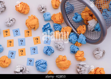 Boules de papier froissé coloré d'interrogation et rouler sur une poubelle. Idée Concept. Banque D'Images