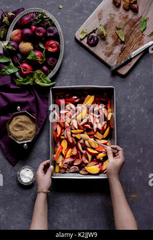 Saupoudrer le sucre plus de fruits coupés, prêts à être réalisés dans d'un fruit cobler Banque D'Images