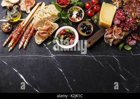 Des en-cas italiens de la nourriture avec du jambon, des tranches de pain ciabatta, olives, fromage Parmesan, Grissini bâtonnets de pain, fromage Feta aux tomates séchées et des saucisses sur da Banque D'Images