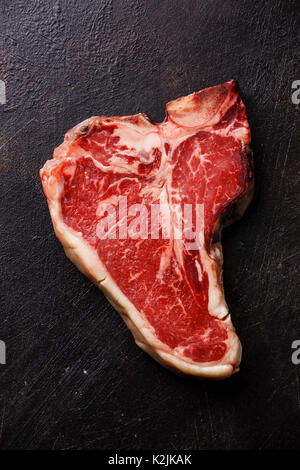 Sec brut de la viande Steak T-bone sur fond sombre Banque D'Images