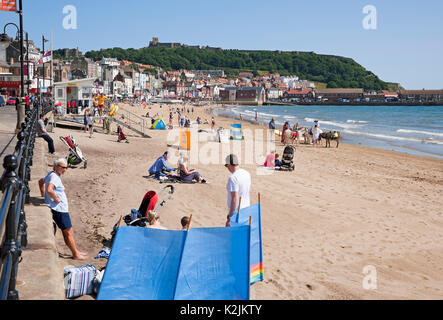 Personnes visiteurs touristes et RNLI station de sauveteur sur la plage en été South Bay Scarborough bord de mer North Yorkshire Angleterre Royaume-Uni Grande-Bretagne Banque D'Images