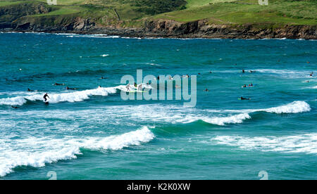 Les vagues de Surfers de l'océan Atlantique à Polzeath Bay à Cornwall, en Angleterre. Banque D'Images