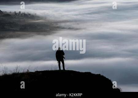 Un photographe solitaire regarde vers le bas sur les nuages d'une montagne Banque D'Images