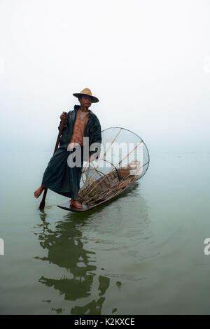 Lac Inle, Myanmar - janvier 04, 2007 : ethnie Intha personnes fisher avec filet de pêche birman traditionnel debout sur l'arrière du bateau long et de l'Aviron Aviron par jambe. Banque D'Images