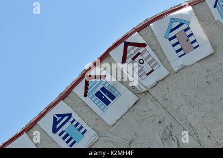 Quelques drapeaux ou banderoles sur le côté d'une cabane de plage montrant des cabines de plage et un thème côtières de la station nautique littoral maritime maritime littoral Banque D'Images