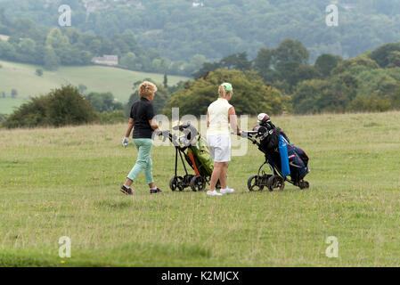 Dame golfeurs dans le sud de la région des Cotswolds England UK. Marcher avec leurs caddies électriques à travers la politique commune à Minchinhampton, Gloucestershire Banque D'Images