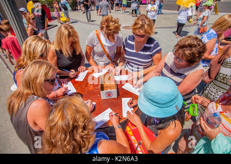 Sponsors remplir des formulaires pour les canards en plastique qui dérivera à terre au surf à partir d'un quai à Huntington Beach, CA. Chacune est numérotée et parrainé et le premier à atteindre le rivage remporte son auteur un prix. Banque D'Images