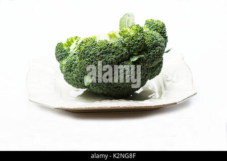 Le brocoli frais dans une assiette sur fond blanc Banque D'Images