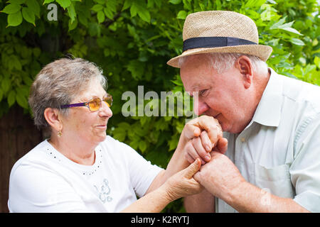 Embrassant sa femme senior man's hands, vieux couple amoureux piscine Banque D'Images