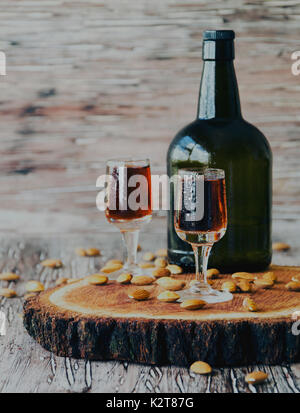 Amaretto liqueur italienne en tasses d'amandes sur une table en bois, selective focus Banque D'Images