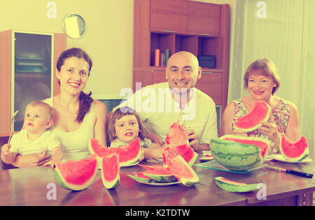 Portrait of happy famille multigénérationnelle eating watermelon at home together Banque D'Images