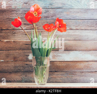 Bouquet de fleurs de tulipes rouges dans un vase en verre sur un fond de grenier en bois close-up conseils Banque D'Images