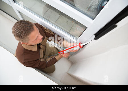 Portrait de jeune homme en appliquant un joint en silicone avec fusil Banque D'Images